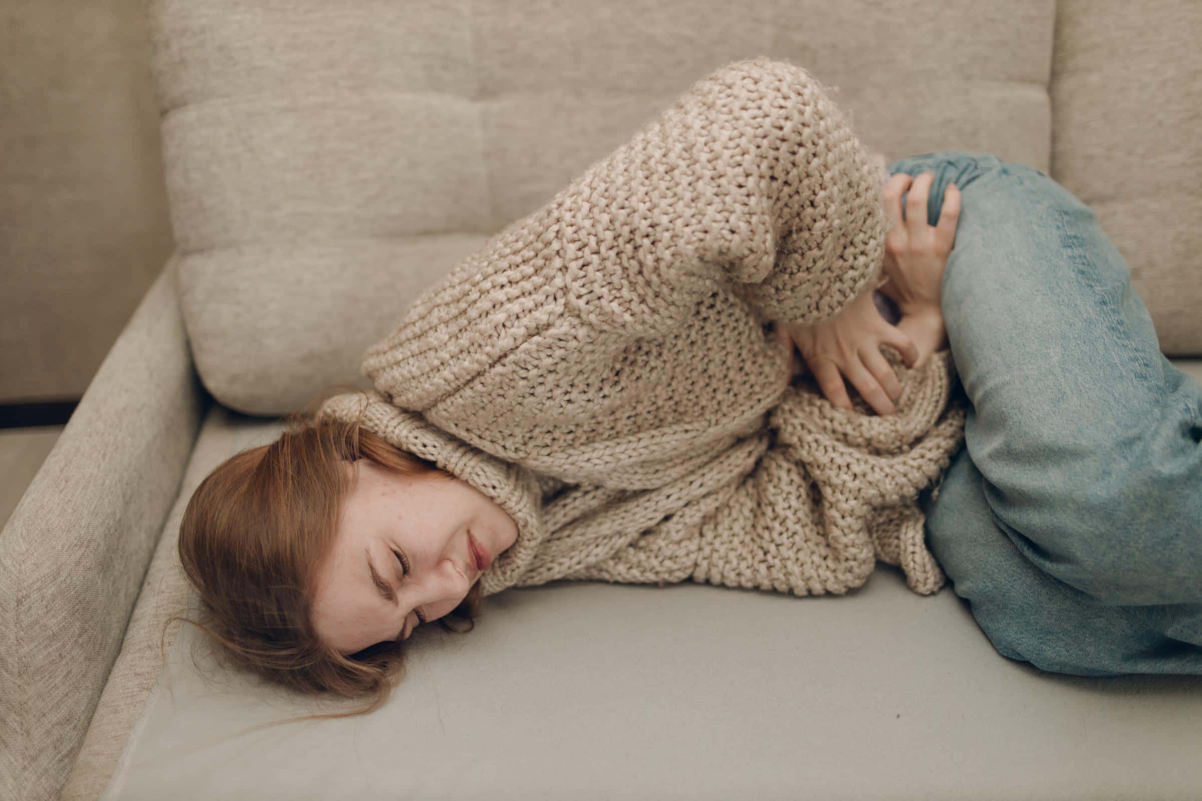 Woman lying in the couch and has stomach-ache